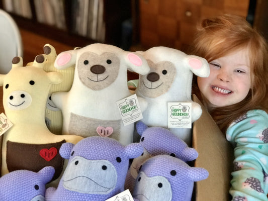 child with Down syndrome smiling with handmade stuffed animals
