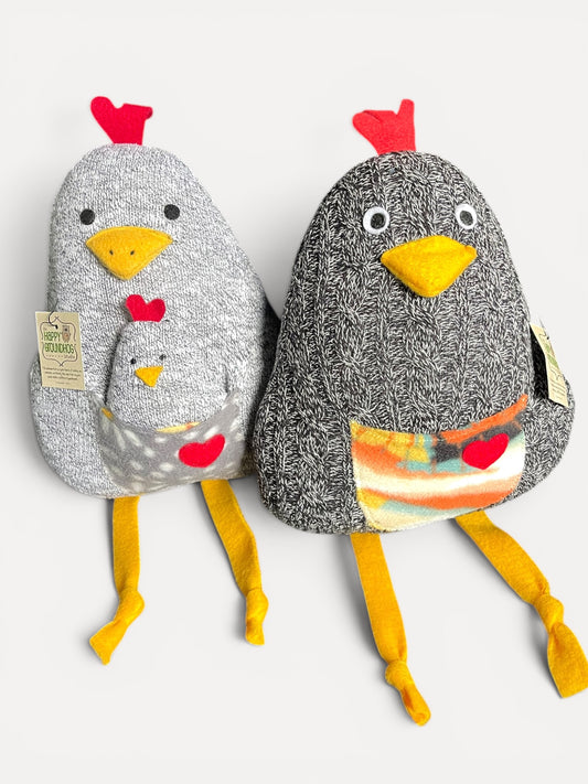 Two plush handmade chickens side by side on a light gray background. One \ is light gray with a speckled texture, red comb, yellow beak and legs, and a small matching pouch.
