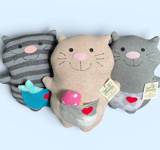 Three plush cat plushie arranged together on a light blue background. The center Kitty  is peach  with a pink nose and a front pocket holding a pink felt ice cream  with white hearts.