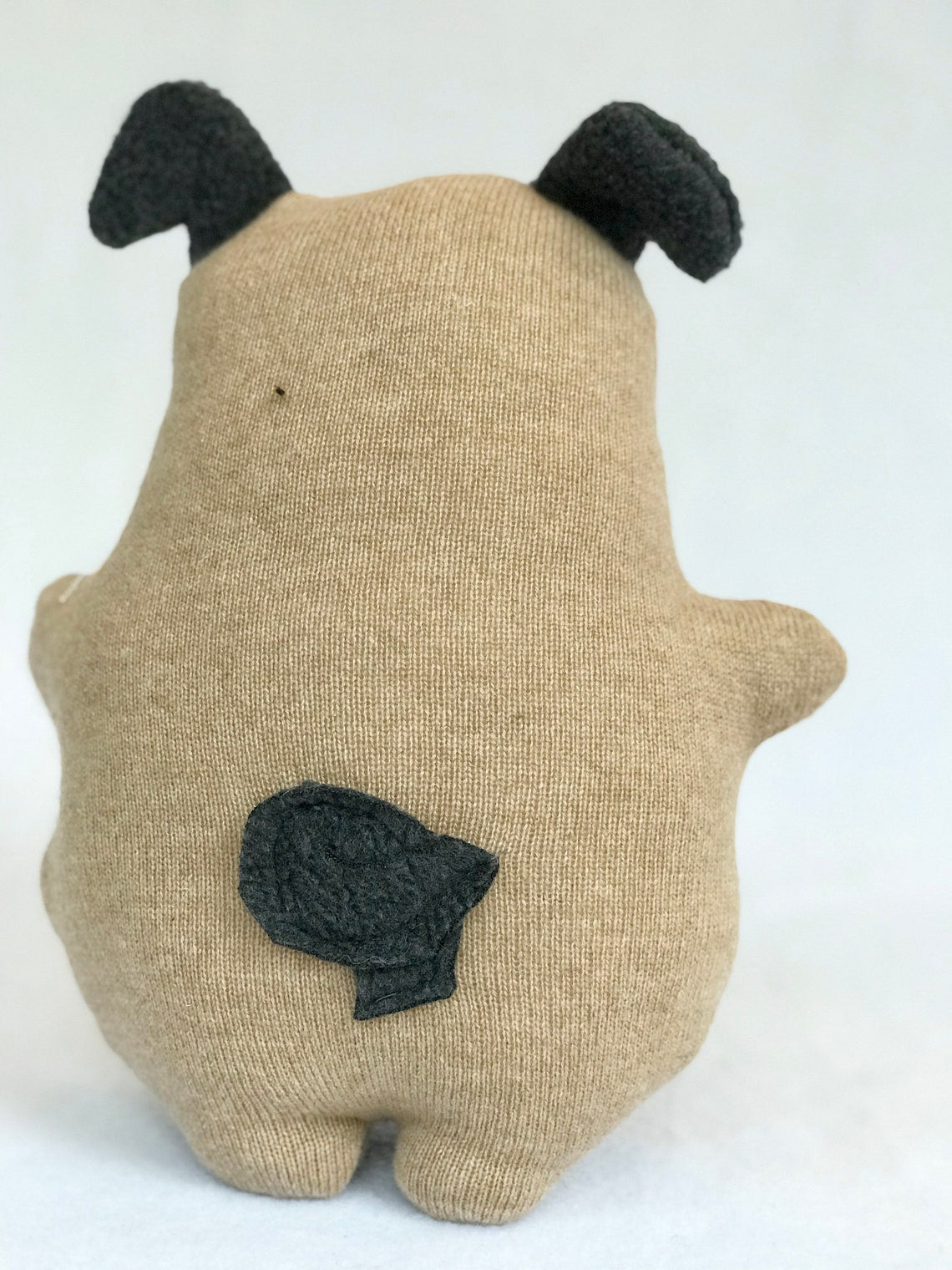 The back of Pug stuffed animal, handmade from up cycled fabrics. Showing curly tail